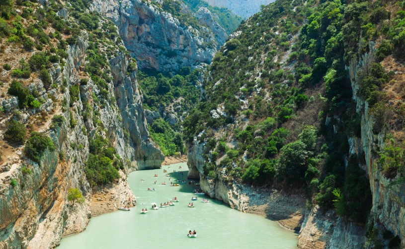 people are canoes and rafters are floating in a blue mountain river