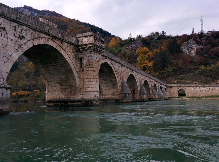 an old bridge on a river that is surrounded by trees