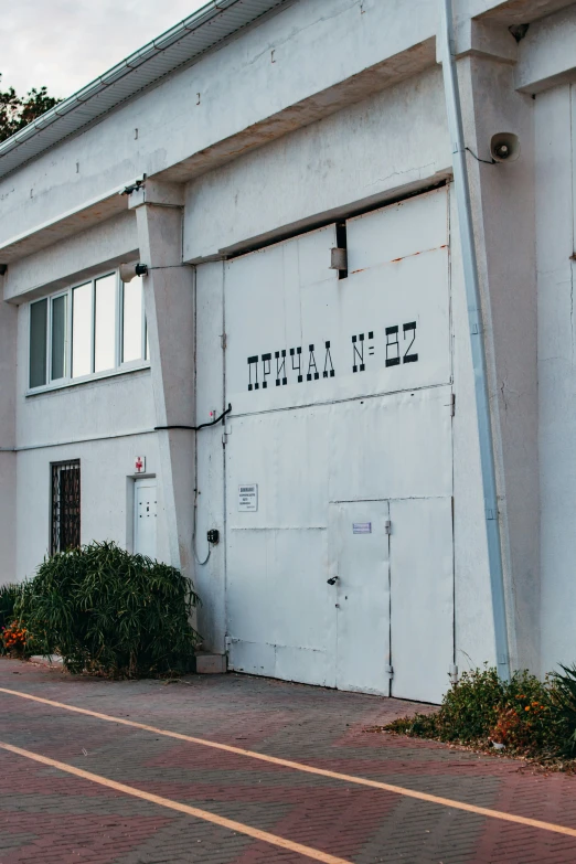 an old white building with a red brick walk way