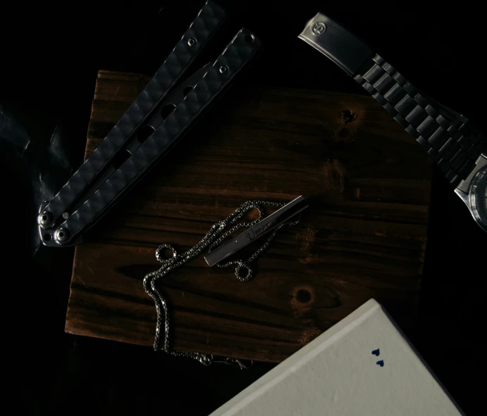 a watch and chains laying on top of a wooden surface