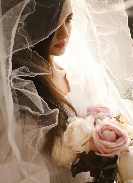 a young woman holding a flower under a veil
