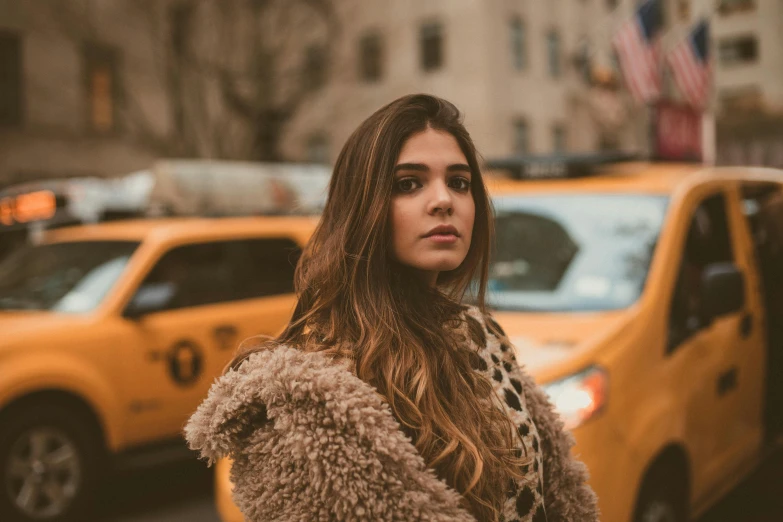 young woman stands in front of taxi cabs and taxis in new york