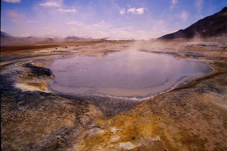 a small pond sits in the middle of a barren, arid plain