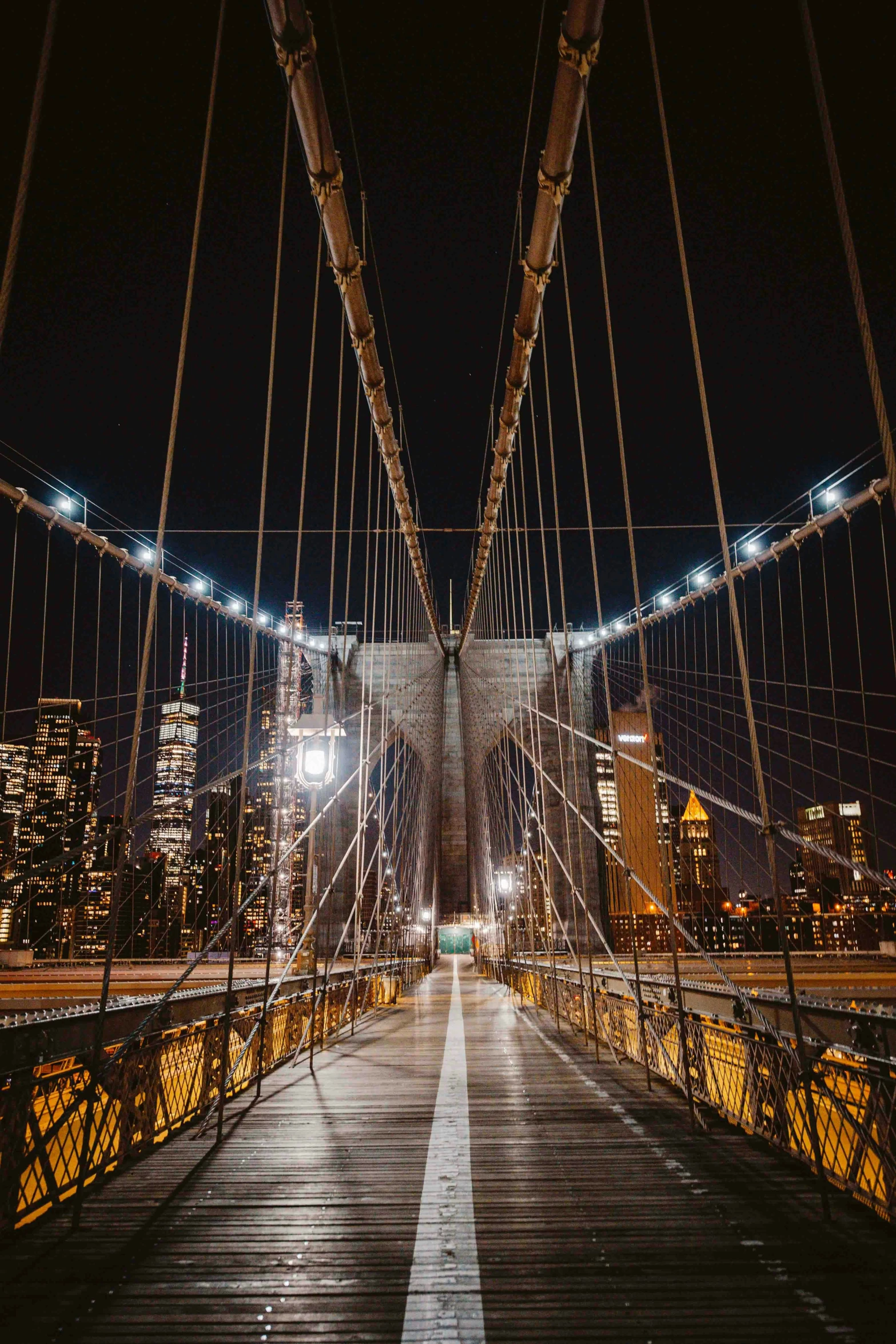 a light of street lights shine on the underside of an old suspension bridge