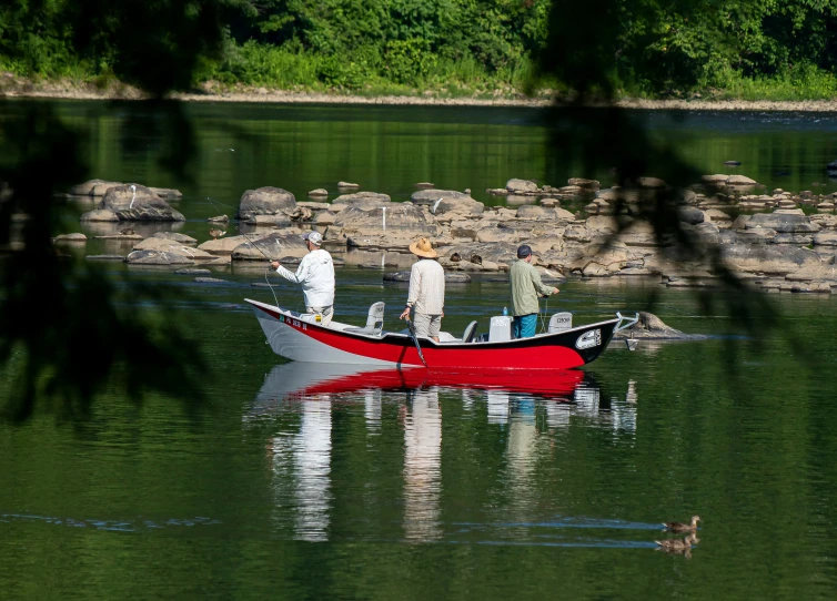 a man and woman fishing with a red boat in the water