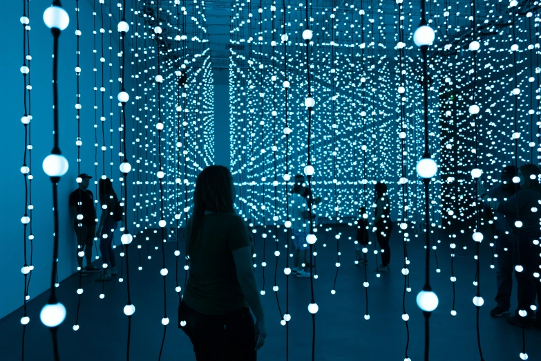 woman standing in front of a screen covered with lights