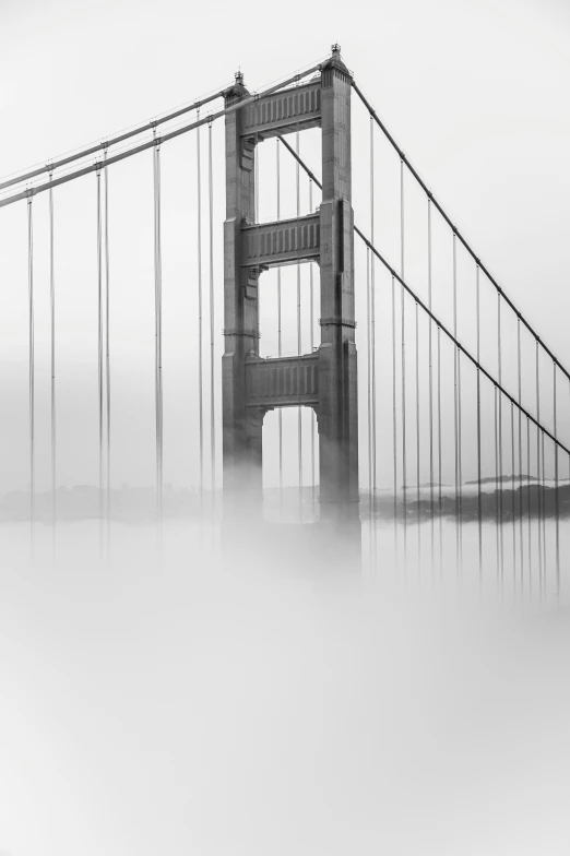 the fog is covering a long bridge in the water