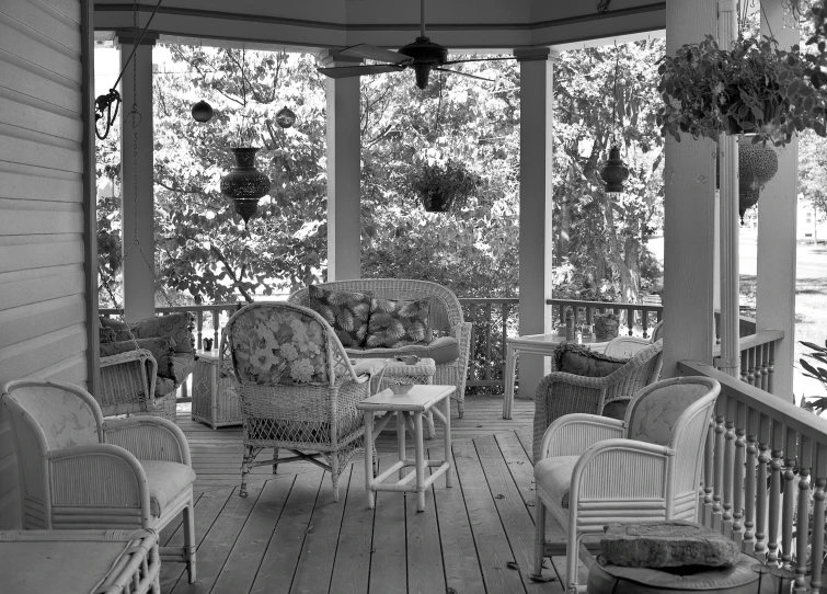 an empty porch with many chairs and tables