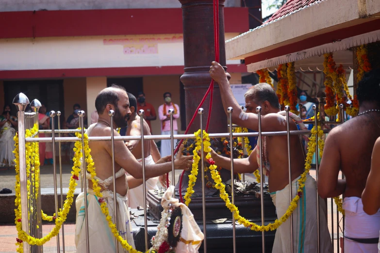 two men fixing rope hanging from poles with yellow beads around them