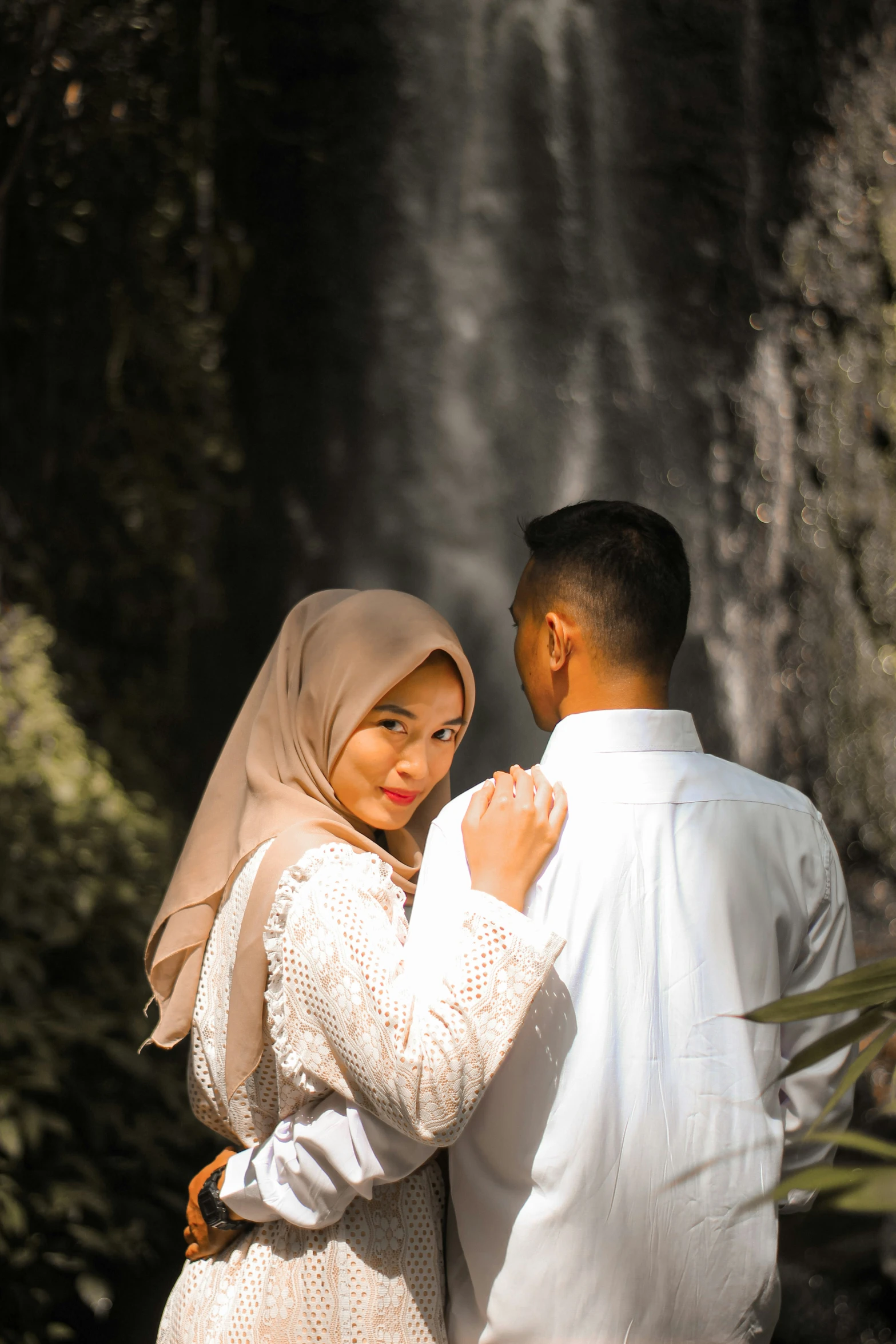 a man and woman standing near a waterfall