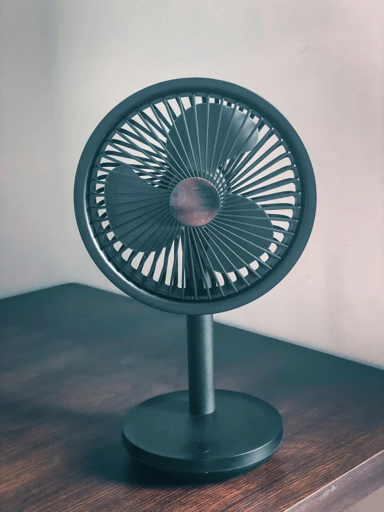 a black fan is placed on a wooden shelf