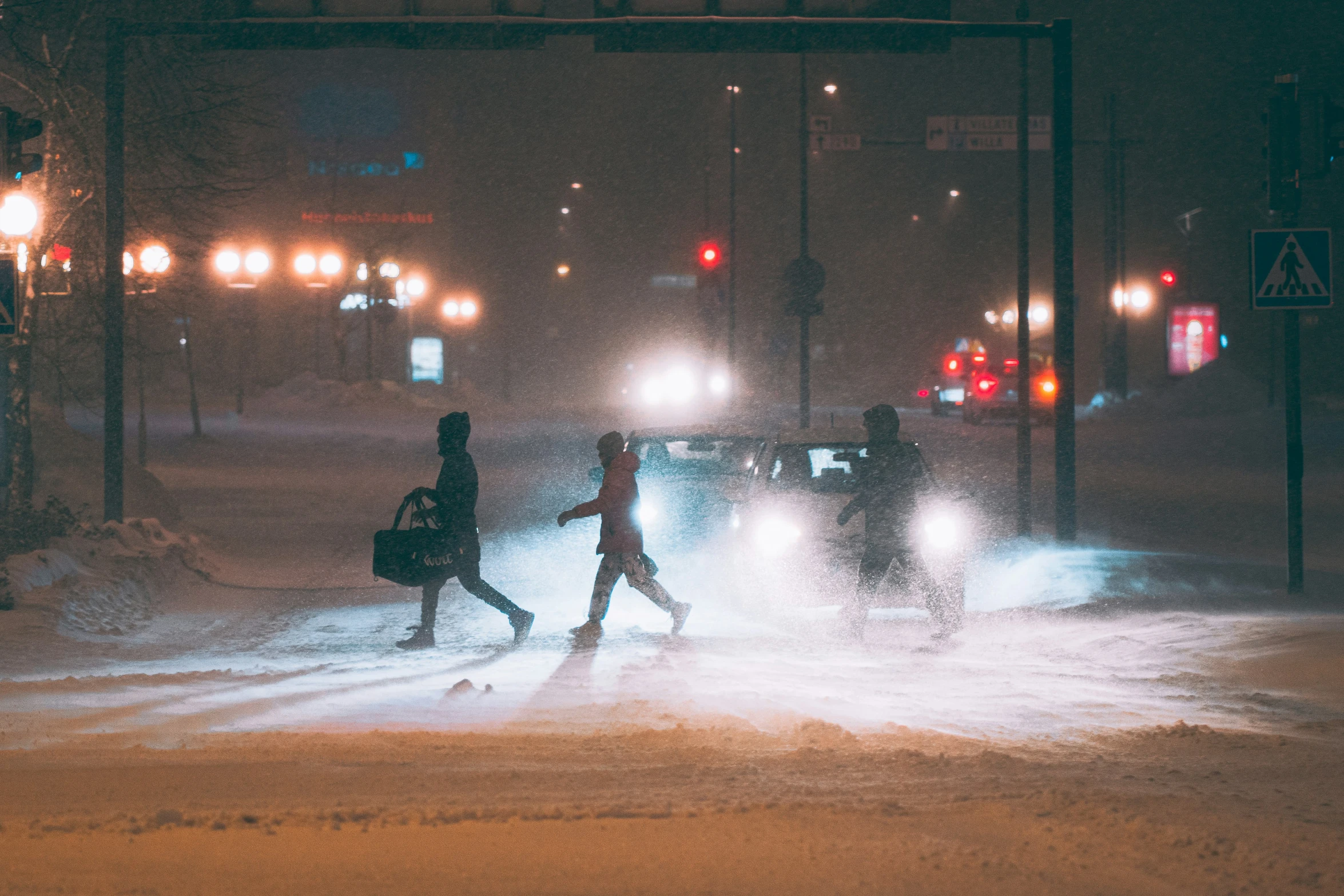 a snow storm on a street with people crossing it