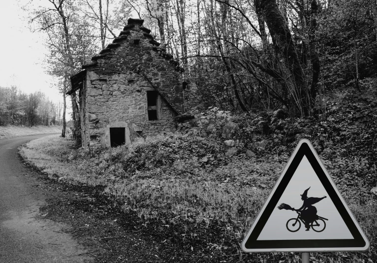 a sign on a dirt road is in front of an old building