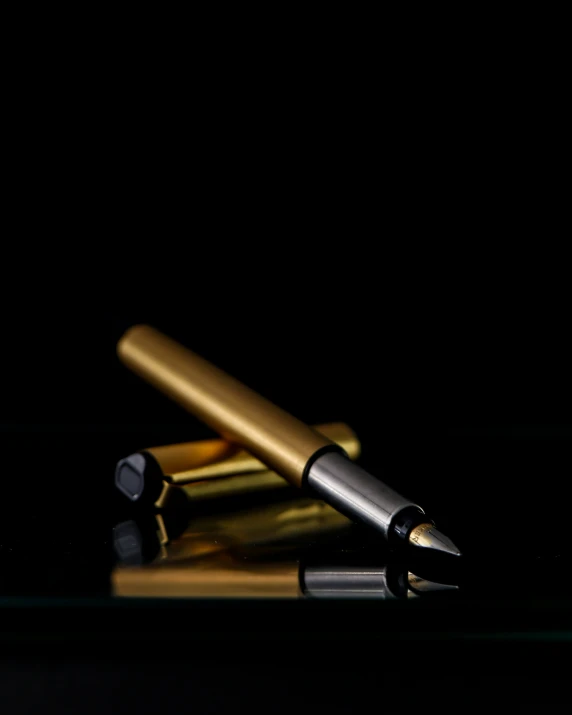 two pens sitting on a black surface