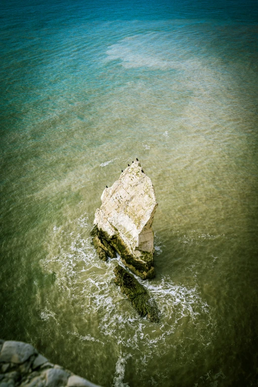 an old broken rock sitting in the middle of a lake