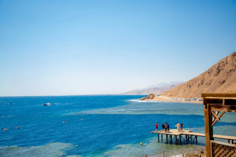 people are standing at a pier near the ocean