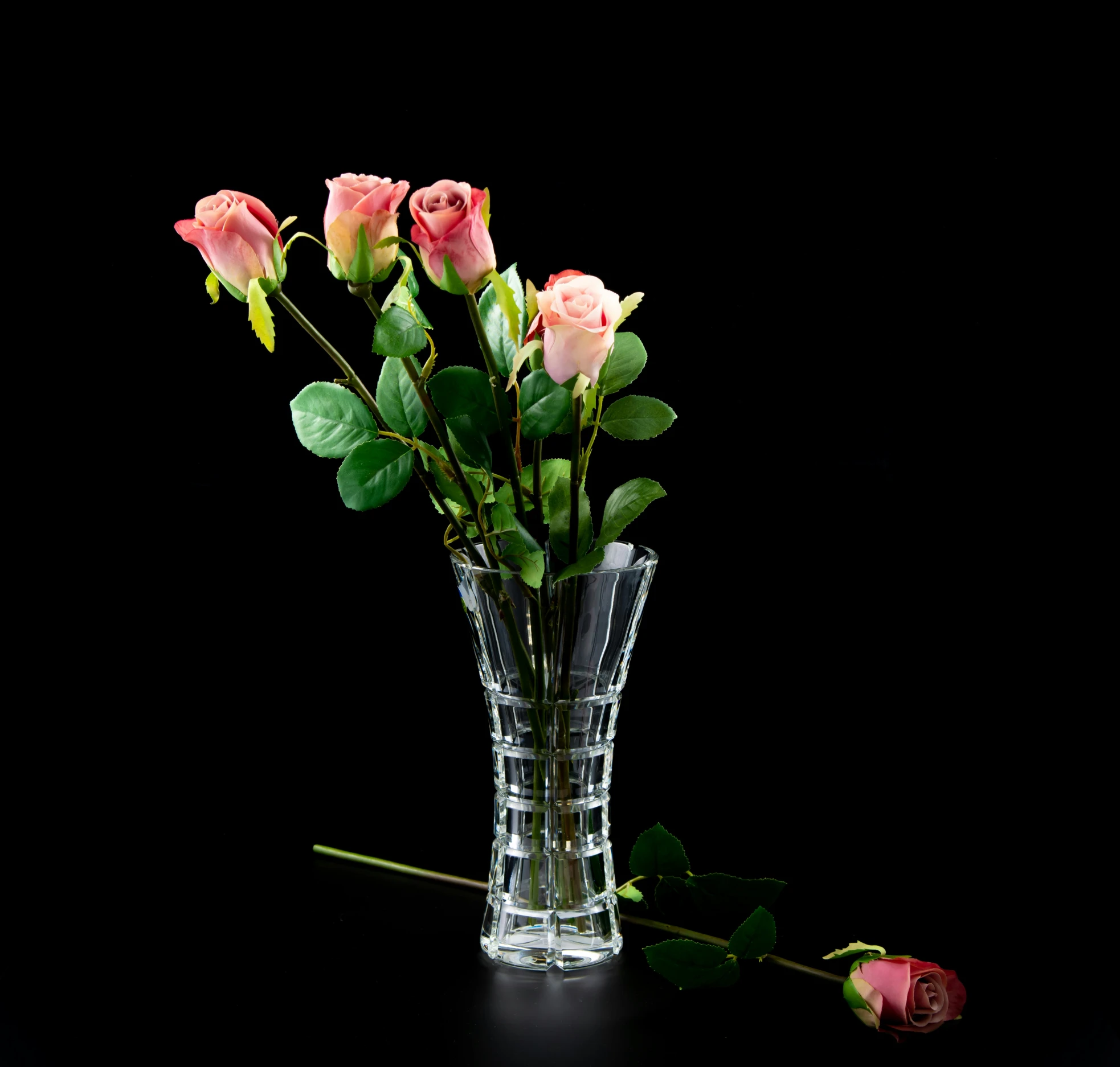 a group of five roses sitting in a vase