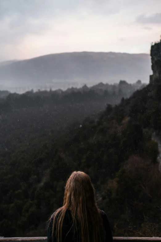 a woman is standing on a hill looking at the valley