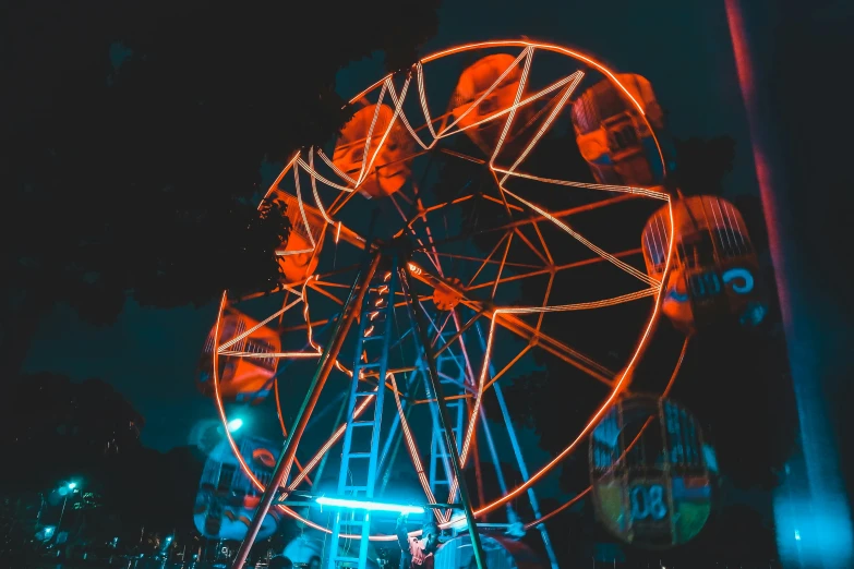 the wheel is lit up at night on the carnival