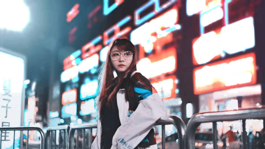 a woman poses for a picture at a night time in front of an electronic board