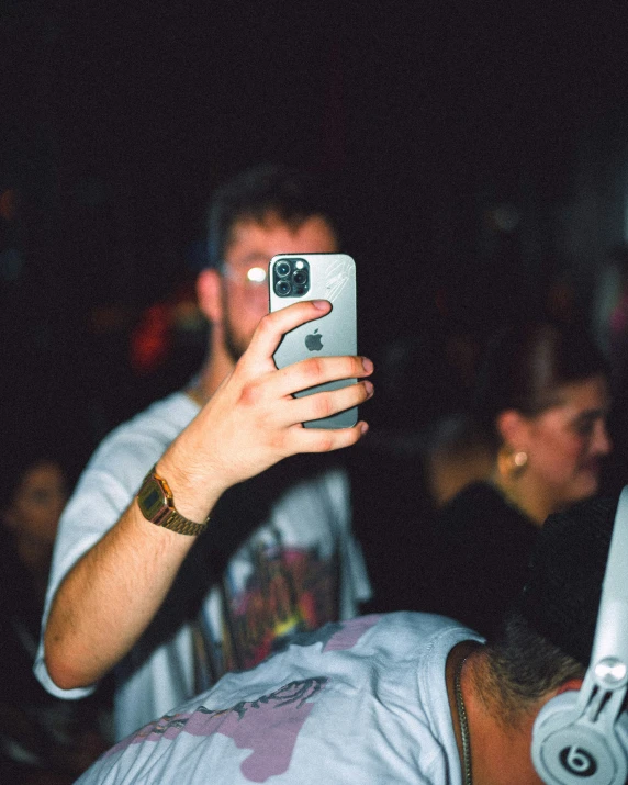 a man taking a picture with his cell phone while a crowd looks on