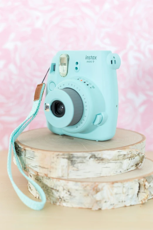 a small blue camera sitting on top of a tree stump