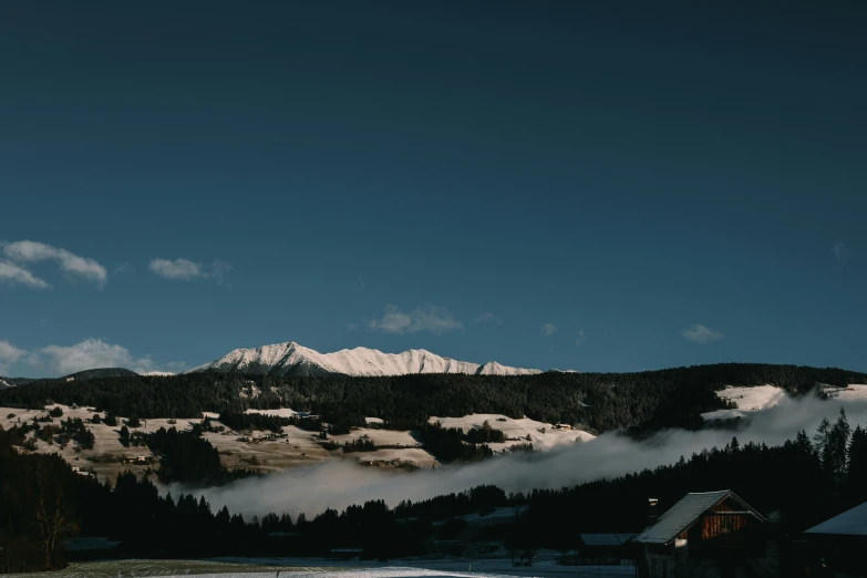 a snowy mountain with some clouds and mist coming out of it