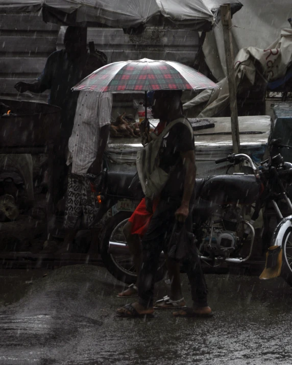 a man stands under an umbrella near other people in the rain