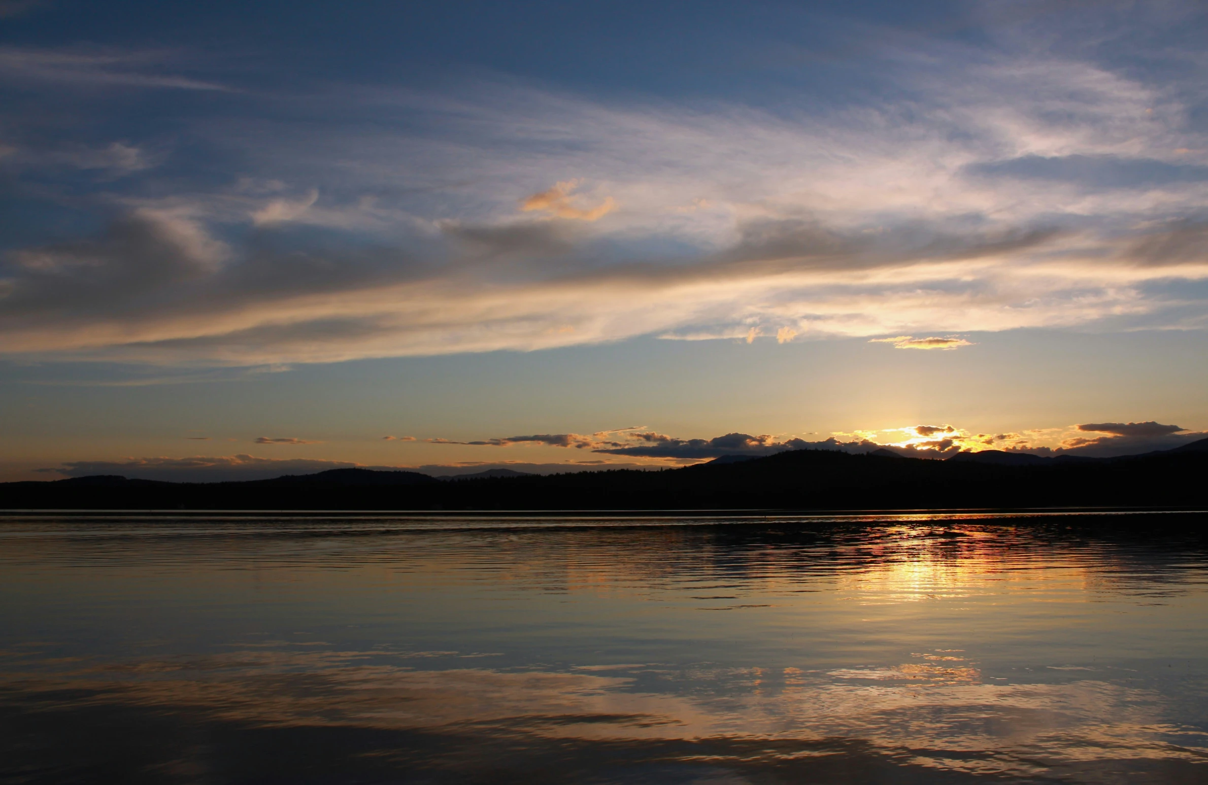 the sunset reflects off of the calm water