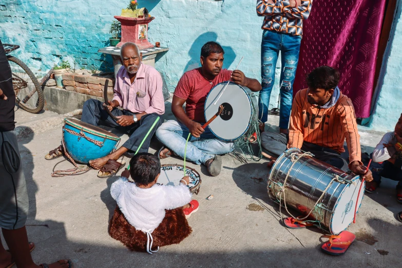 several men are playing an instrument while sitting on the ground