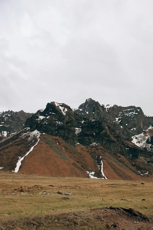 a lone mountain range in the snow on a cloudy day