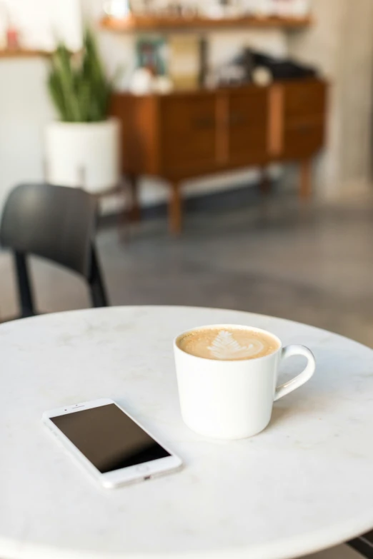 a cell phone and a cup of coffee are on a table