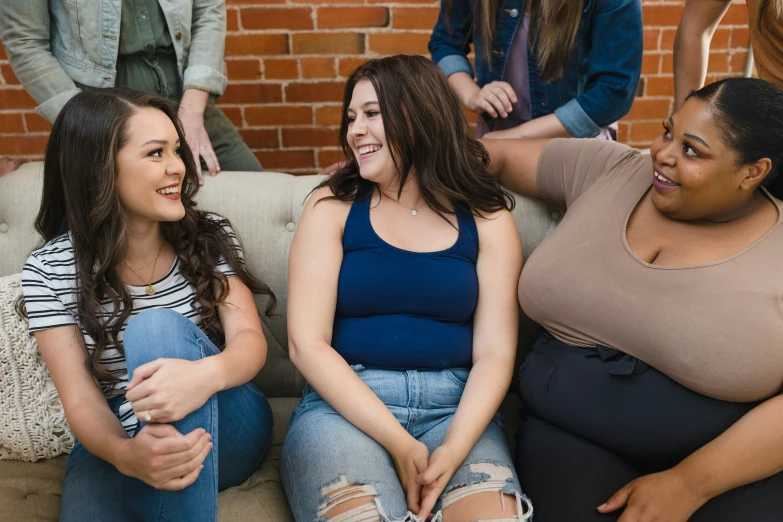 three smiling women sit on the couch and laugh