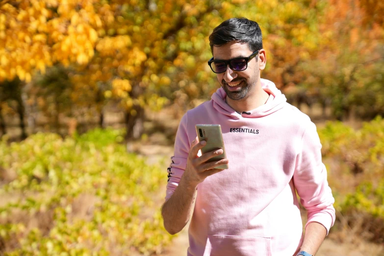 a man in pink hooded sweatshirt holding an electronic device