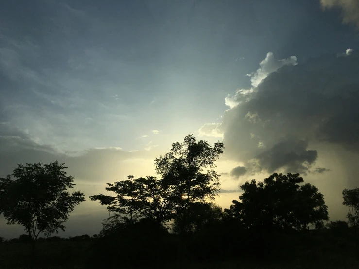 a dark storm approaches over the trees and hill