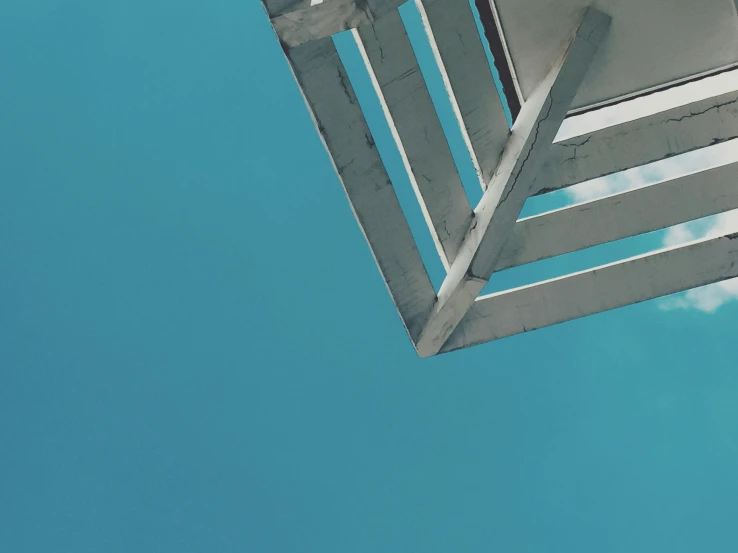 the back view of the top of a wooden bench with white posts against a blue sky