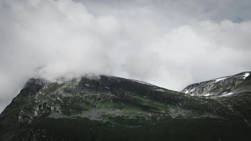 a lush green mountain with mountains in the background