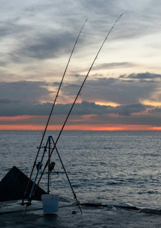 fishing rod and pole in the water with sunset behind it