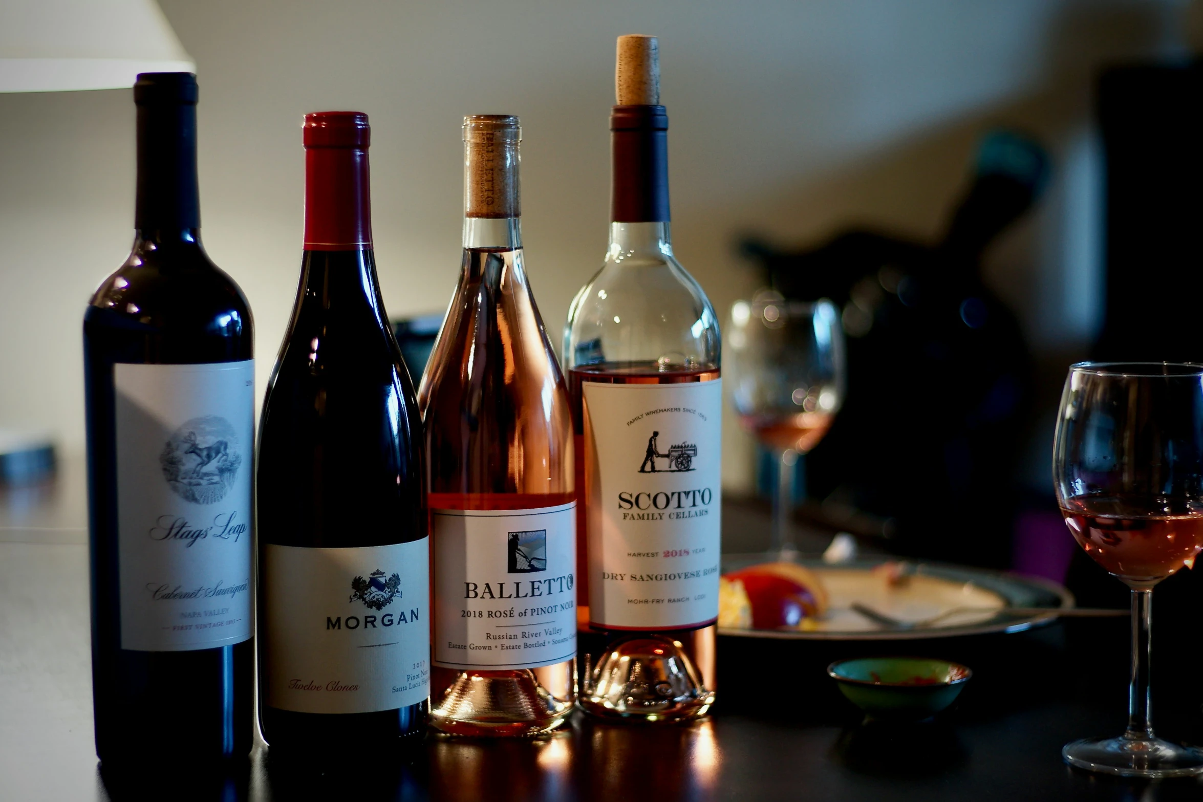 a bunch of bottles on a table with a glass and plate