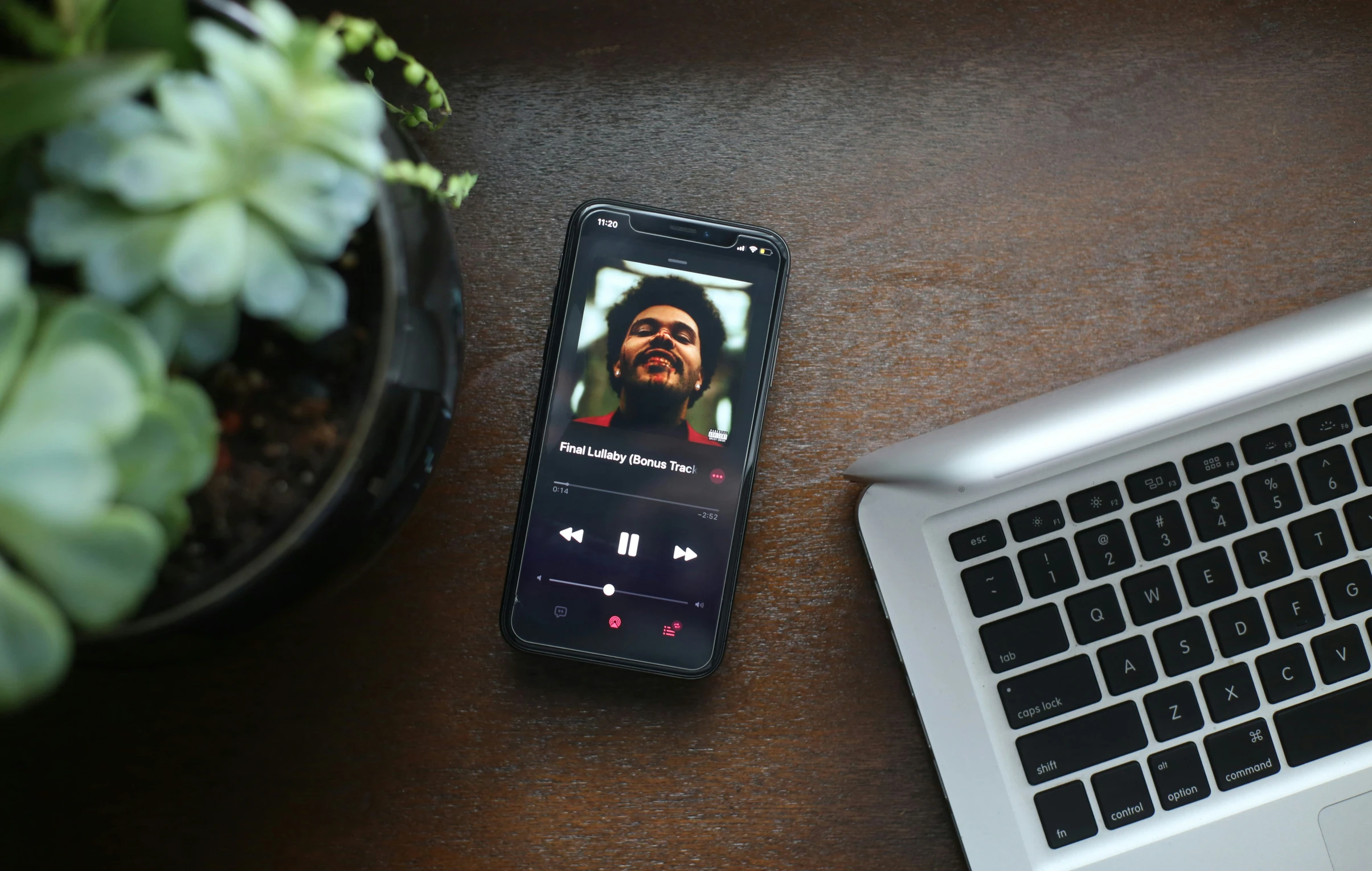 an mp3 player resting on a wooden desk near a laptop