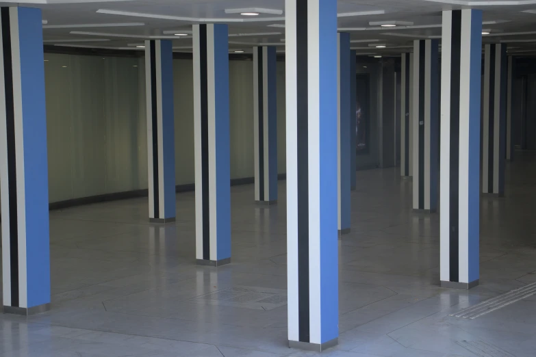 a row of blue and white striped pillars in an empty warehouse