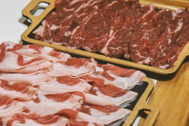 two trays filled with sliced meat next to one another