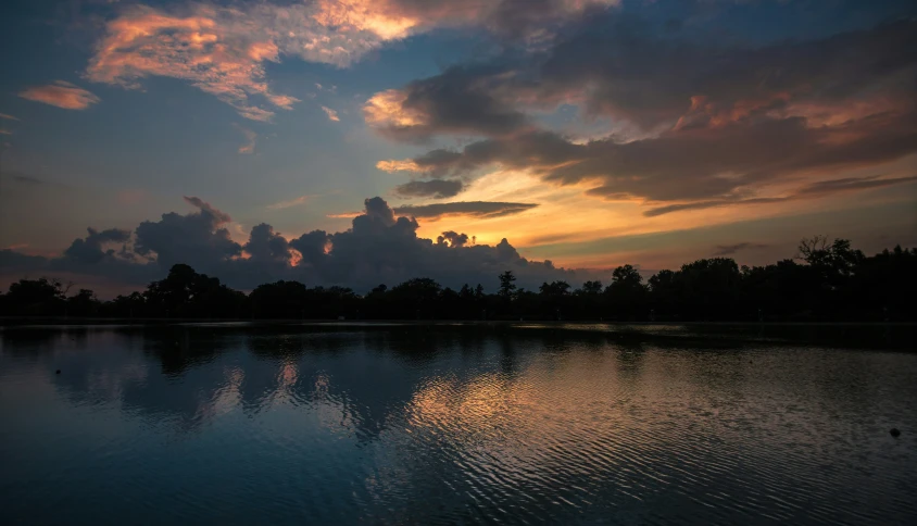 a sunset reflects in the waters of a lake