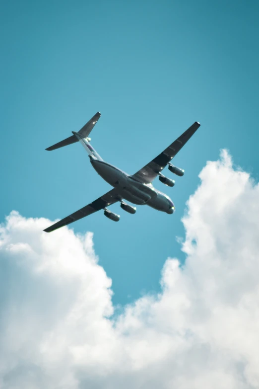 a large airplane in the air with clouds and blue sky