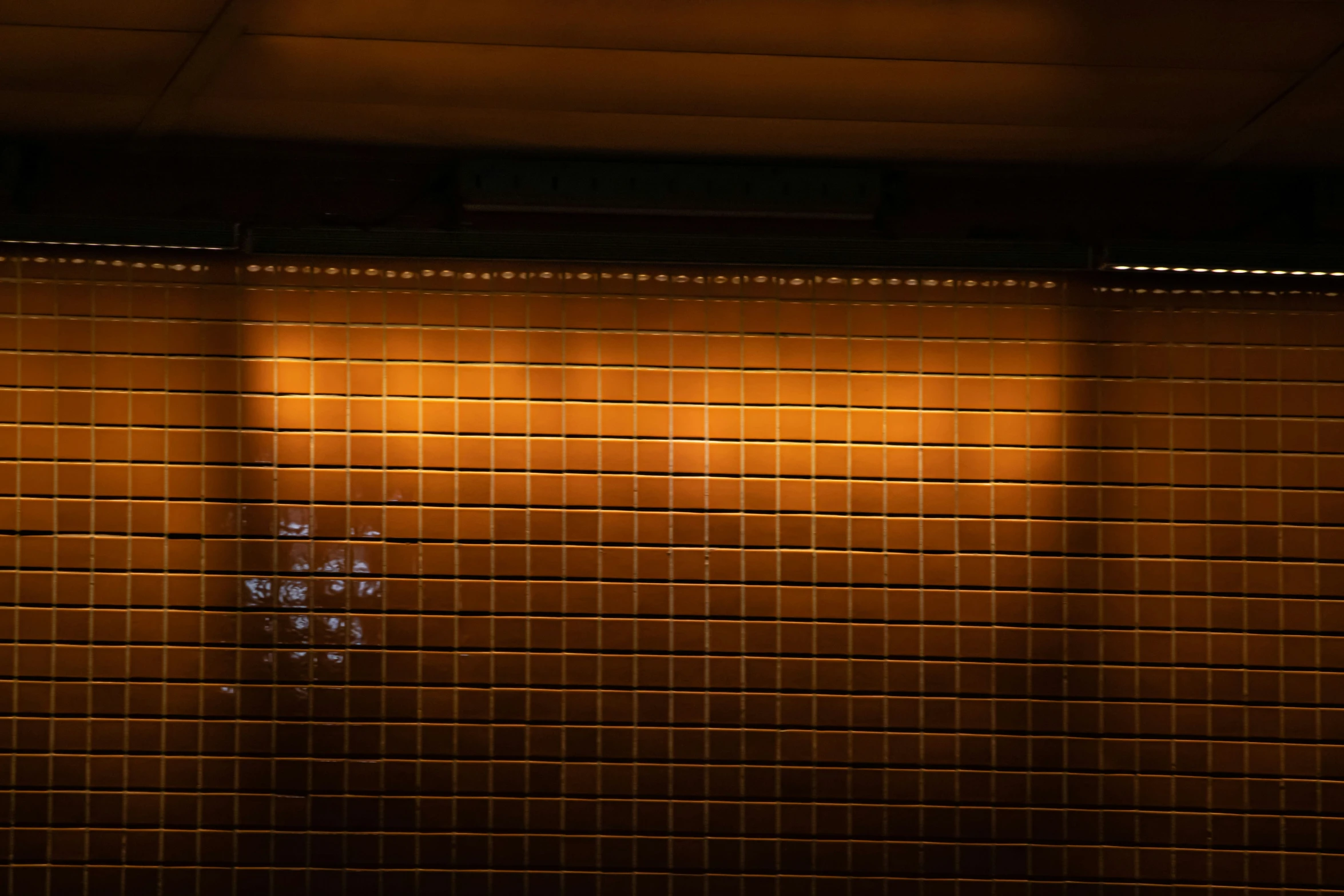 a tiled wall next to a metal door and street light