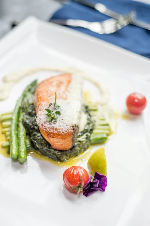 fish and vegetables on a white plate with fork and spoon