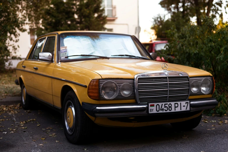 an old mercedes sitting in the street with trees around