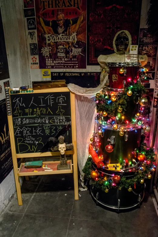 a decorated christmas tree is behind a small chalkboard in an alleyway