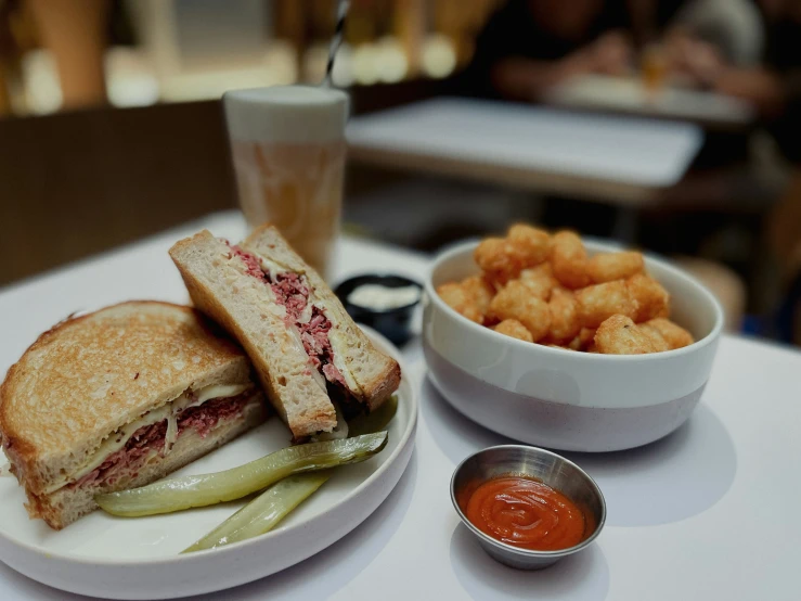 a sandwich on a plate next to a bowl of fries