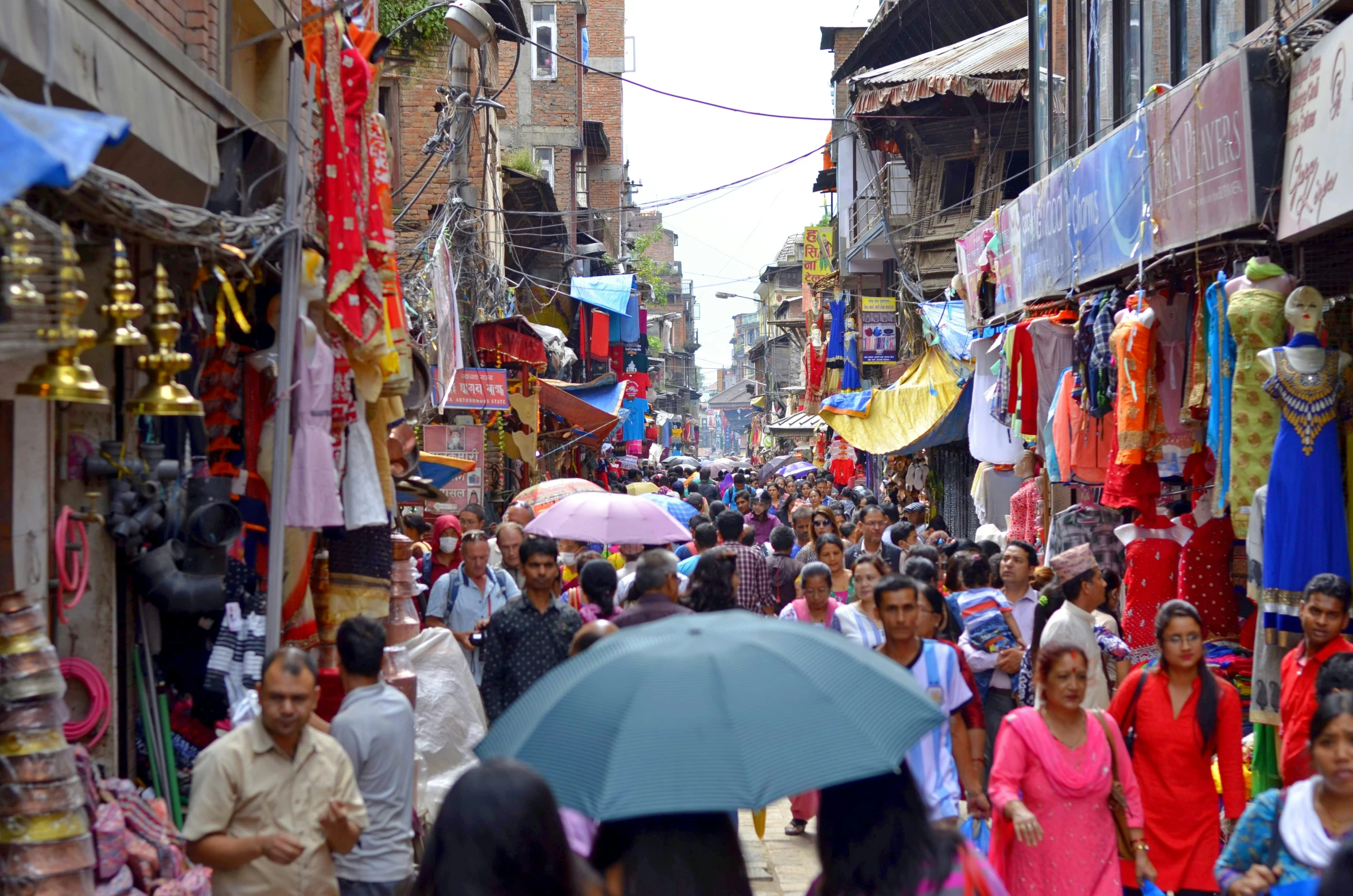 many people are walking down the street by shops